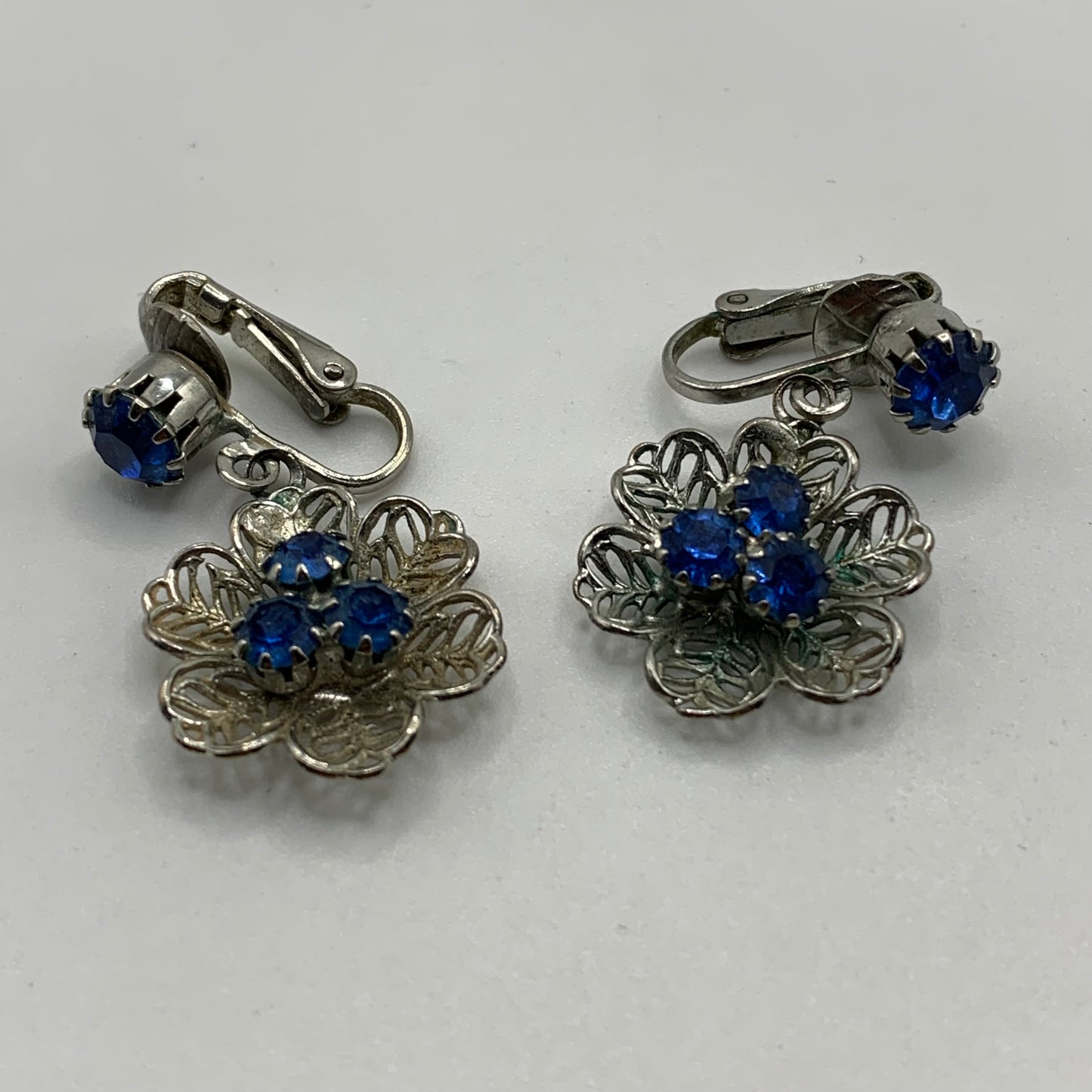 Vintage unsigned silver tone filigree flower blue rhinestone screw back earrings